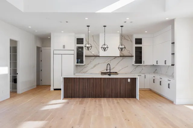 a large kitchen with cabinets a sink a window and stainless steel appliances