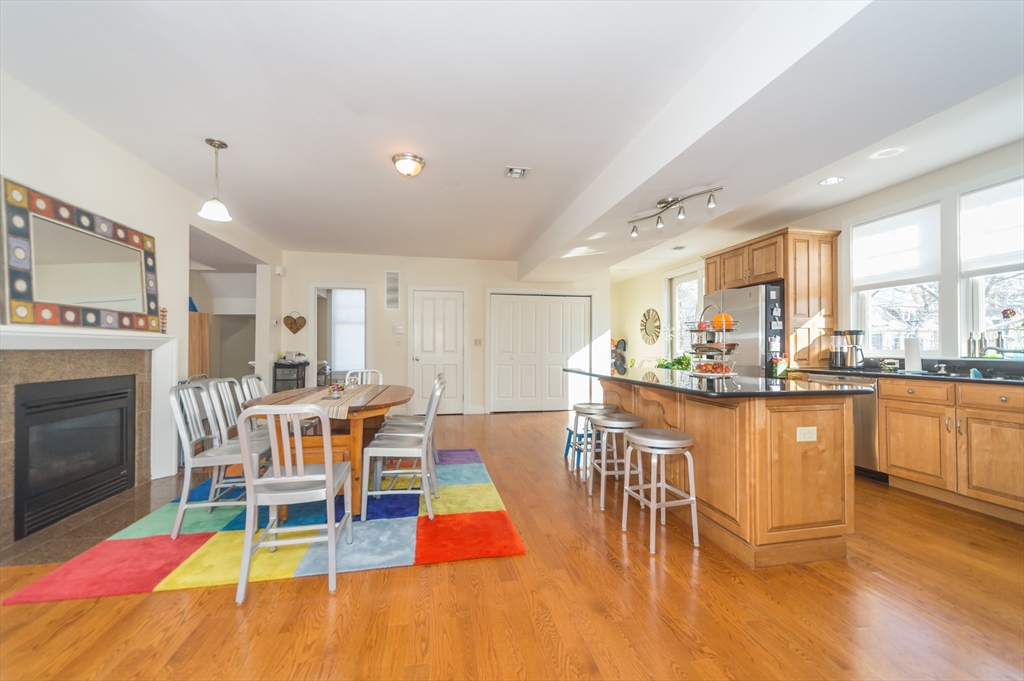 53 Winslow Road, Unit A Brookline, MA 02446 - Photo 9 of 16 a dining area with stainless steel appliances granite countertop a stove top oven a dining table and a fireplace