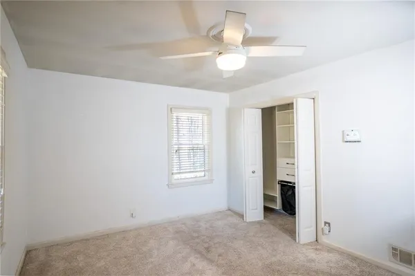 an empty room with chandelier fan and windows