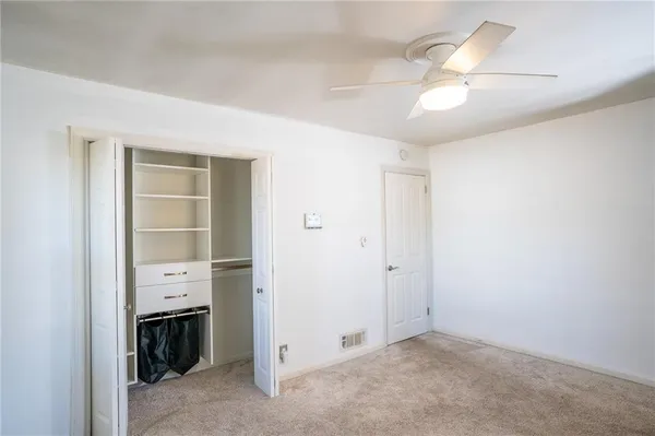 an empty room with a fireplace and chandelier fan