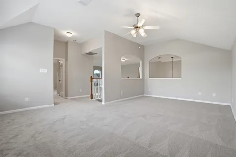 an empty room with chandelier fan and windows