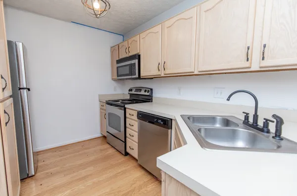 a kitchen with stainless steel appliances granite countertop a sink and cabinets with wooden floor