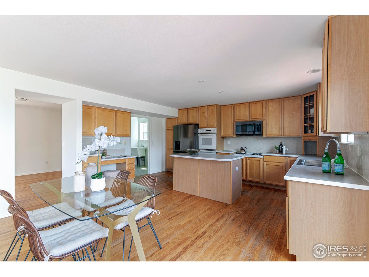 1414 Hoffman Drive Erie, CO 80516 - Photo 14 of 37 a kitchen with stainless steel appliances kitchen island granite countertop a refrigerator a stove a sink dishwasher with a dining table and chairs with wooden floor