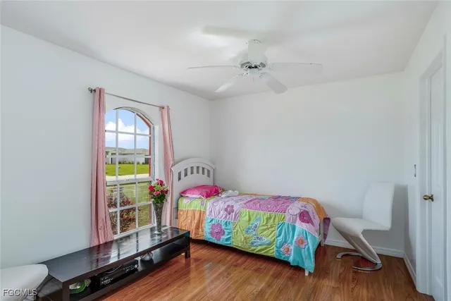 a bedroom with a bed a dresser and wooden floor
