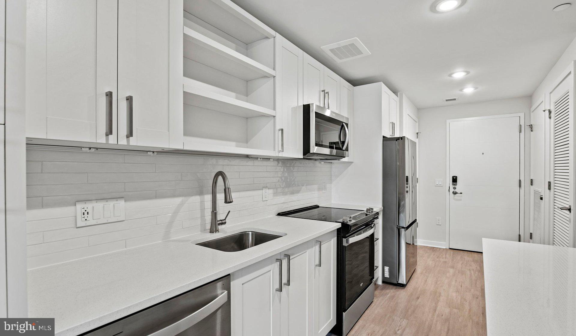 a kitchen with stainless steel appliances a sink stove and white cabinets