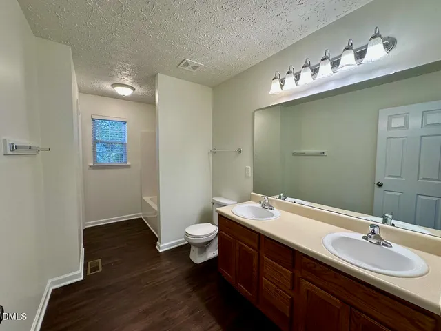 a bathroom with a tub a sink and wooden floor