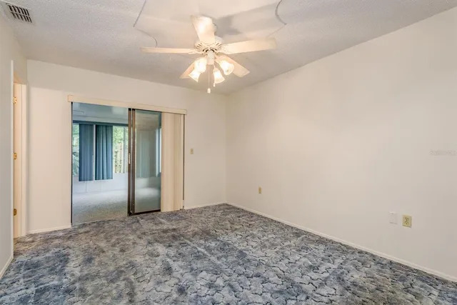 an empty room with a chandelier fan and closet