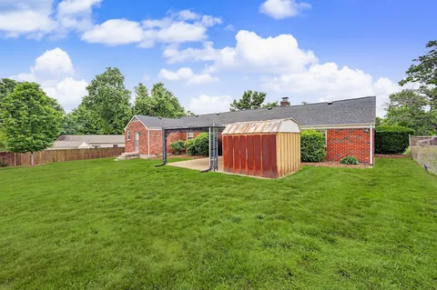 a backyard of a house with table and chairs plants and large tree