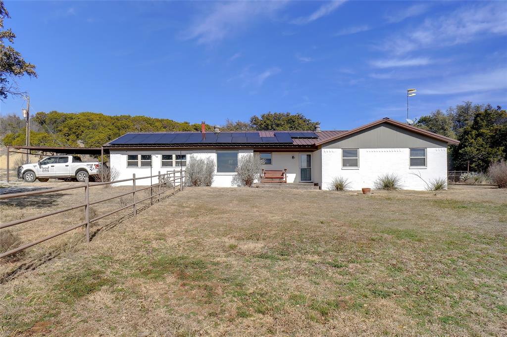 View of front of home with solar panels and a front lawn