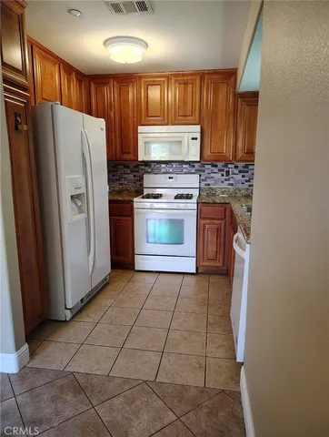 a kitchen with granite countertop a refrigerator and a stove top oven