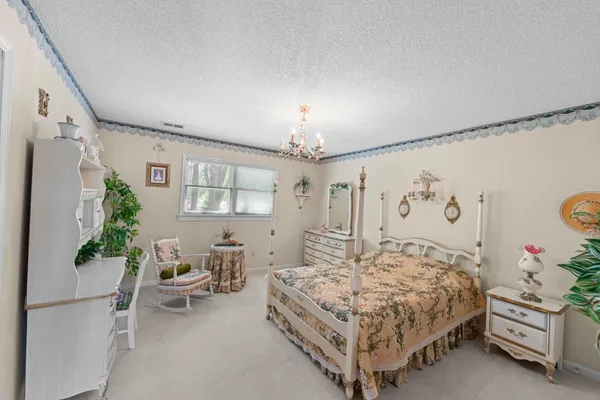 a bedroom with a bed chandelier and a window