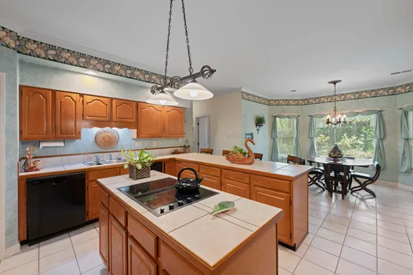 a kitchen with a stove a sink dishwasher a dining table and chairs with wooden floor