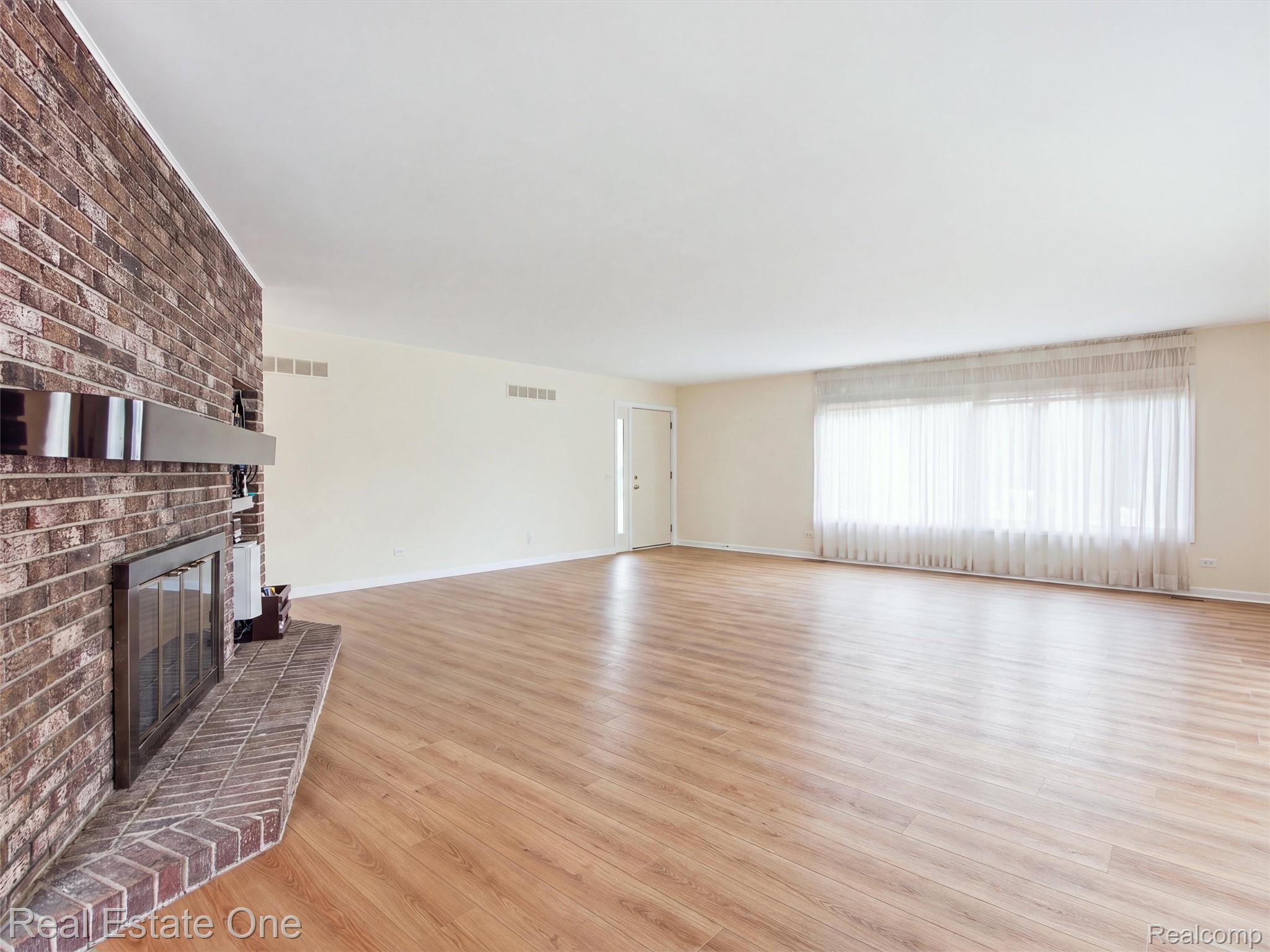 2626 West Wattles Road Troy, MI 48098 - Photo 9 of 65 Spacious room featuring brick fireplace, wood-finish flooring, white walls, and large windows