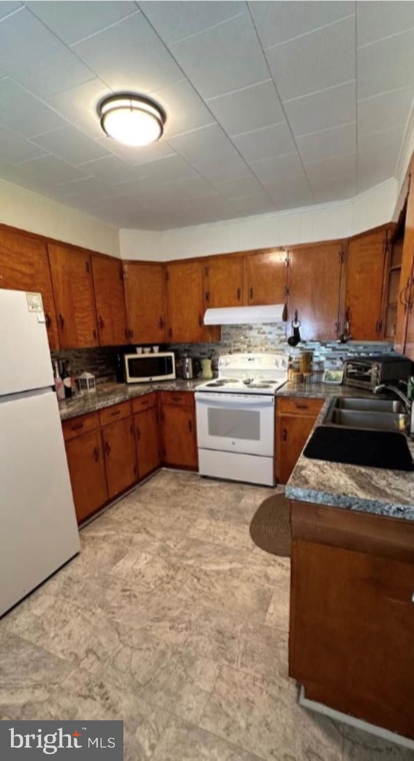 409 Myrtle Street Crisfield, MD 21817 - Photo 11 of 19 a kitchen with a stove a sink and a refrigerator