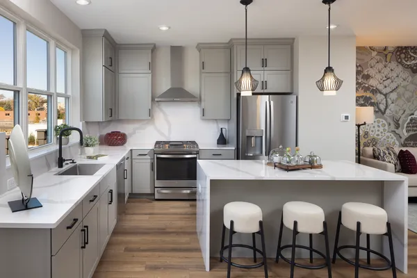 a kitchen with stainless steel appliances granite countertop a sink a stove a refrigerator and island with wooden floor