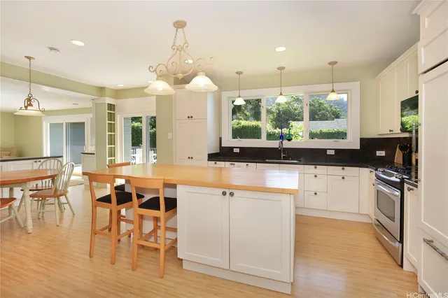 a kitchen with stainless steel appliances granite countertop a stove top oven a sink dishwasher a dining table and chairs with wooden floor