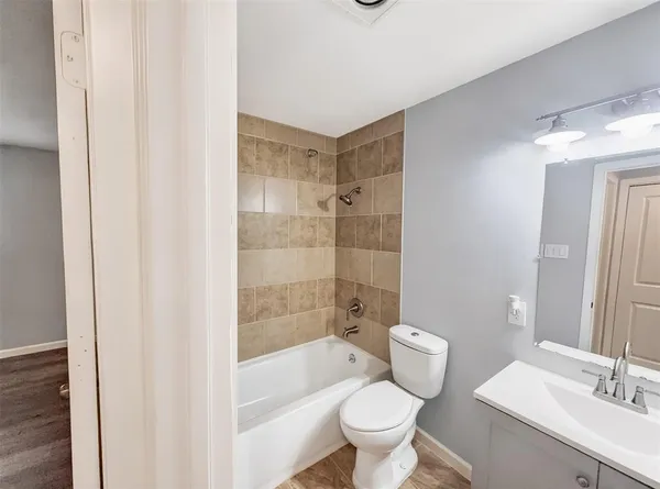 a bathroom with a bathtub shower sink mirror and toilet