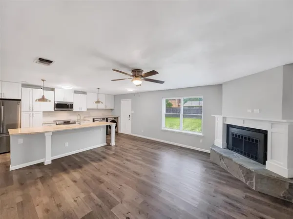a open kitchen with granite countertop a stove top oven a sink dishwasher and a fireplace with wooden floor