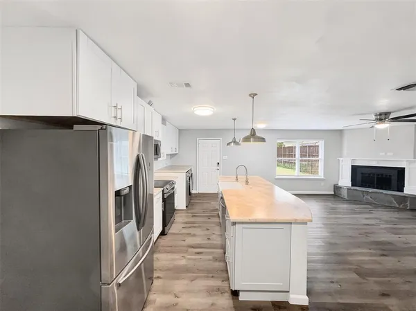 a kitchen with stainless steel appliances kitchen island a refrigerator sink and fireplace