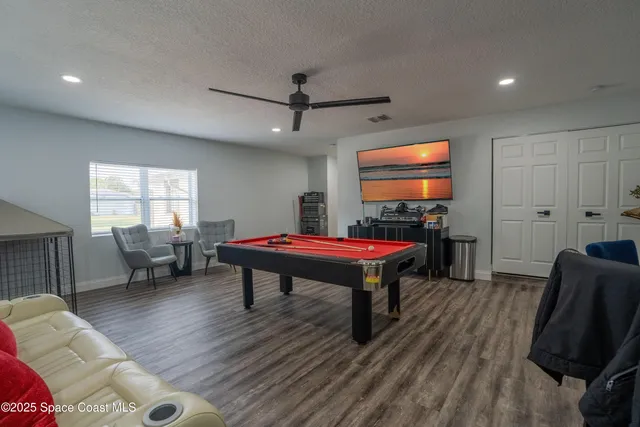 a room with furniture pool table flat screen tv and windows