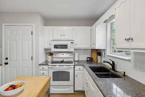 a kitchen with stainless steel appliances granite countertop a stove a sink and a refrigerator
