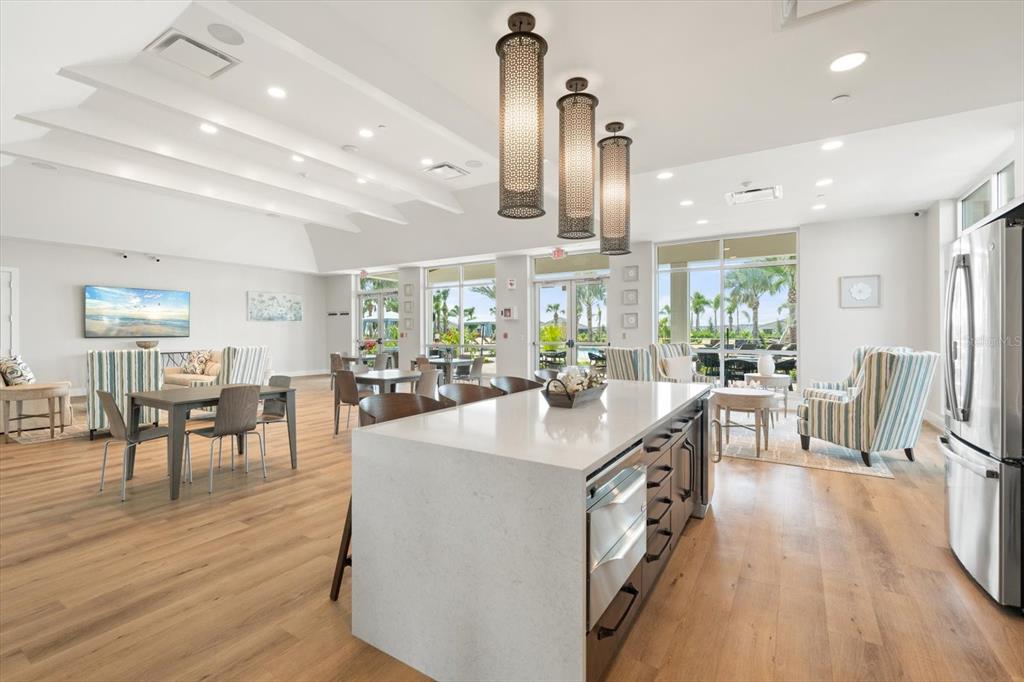 17738 Pastureland Avenue Lakewood Ranch, FL 34211 - Photo 42 of 50 a kitchen with stainless steel appliances a dining table chairs stove and a wooden floor