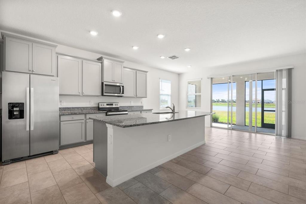 17738 Pastureland Avenue Lakewood Ranch, FL 34211 - Photo 6 of 50 a large kitchen with a large window and stainless steel appliances