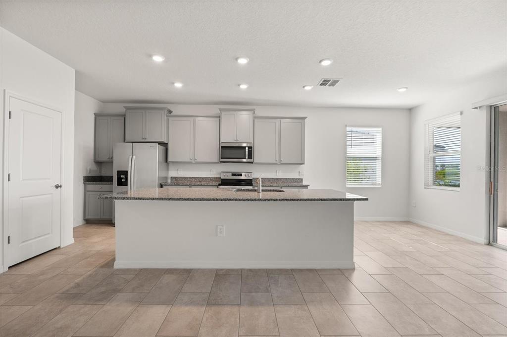 17738 Pastureland Avenue Lakewood Ranch, FL 34211 - Photo 7 of 50 a large kitchen with kitchen island a sink a stove a refrigerator and white cabinets