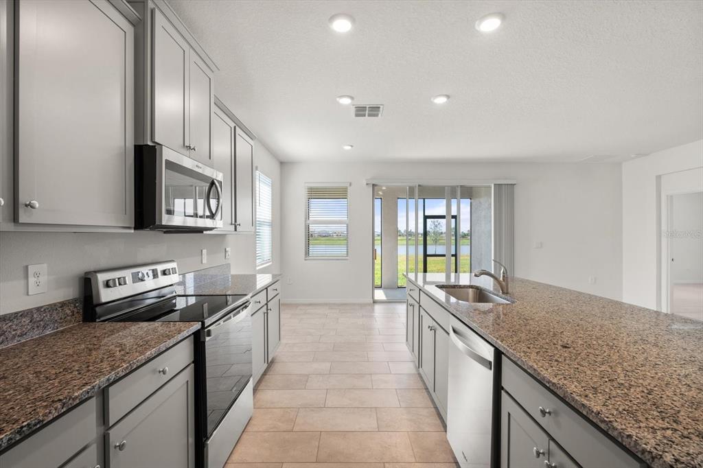 17738 Pastureland Avenue Lakewood Ranch, FL 34211 - Photo 10 of 50 a large kitchen with kitchen island granite countertop a sink and dishwasher a oven with granite countertops