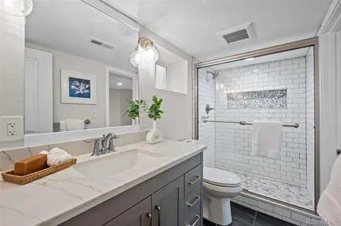 a bathroom with a granite countertop sink mirror vanity and toilet