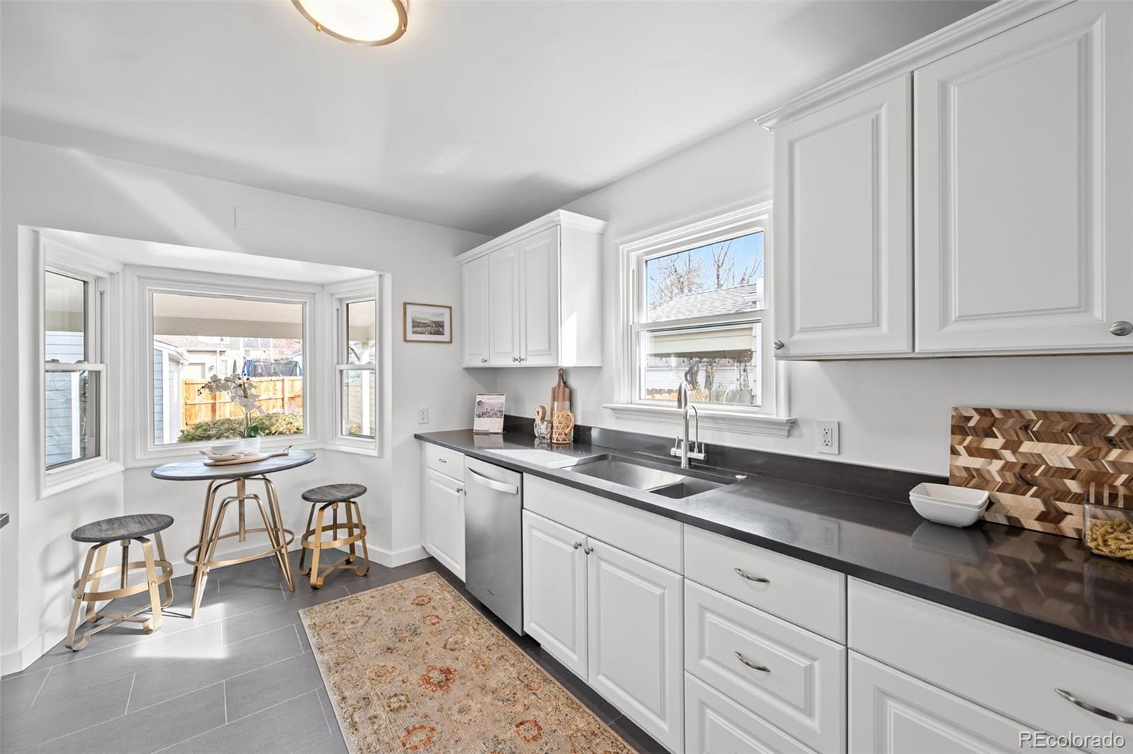 2344 South Lafayette Street Denver, CO 80210 - Photo 8 of 32 a kitchen with granite countertop a sink white cabinets and window