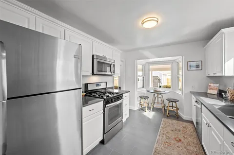 a kitchen with a refrigerator a stove a sink a dining table and chairs