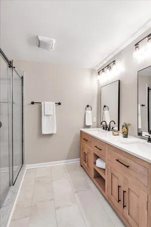 a spacious bathroom with a double vanity sink a mirror and a shower