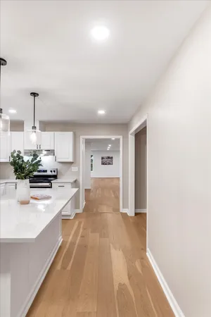 a view of a kitchen with kitchen island a sink wooden floor and living room view