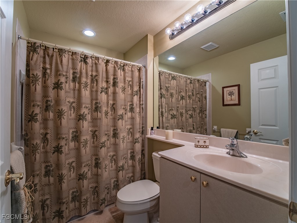 20311 Rookery Drive Estero, FL 33928 - Photo 25 of 29 a bathroom with a sink a toilet a mirror a vanity and shower