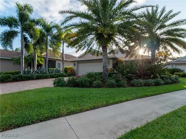 a view of a house with a yard and palm trees