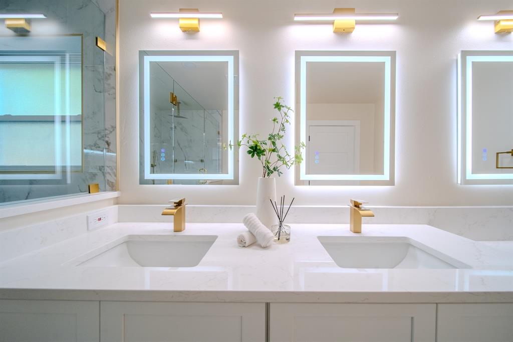 5125 Ashbrook Road Dallas, TX 75227 - Photo 23 of 34 Dual integrated sinks with gold-finish faucets, illuminated mirrors, and white countertops