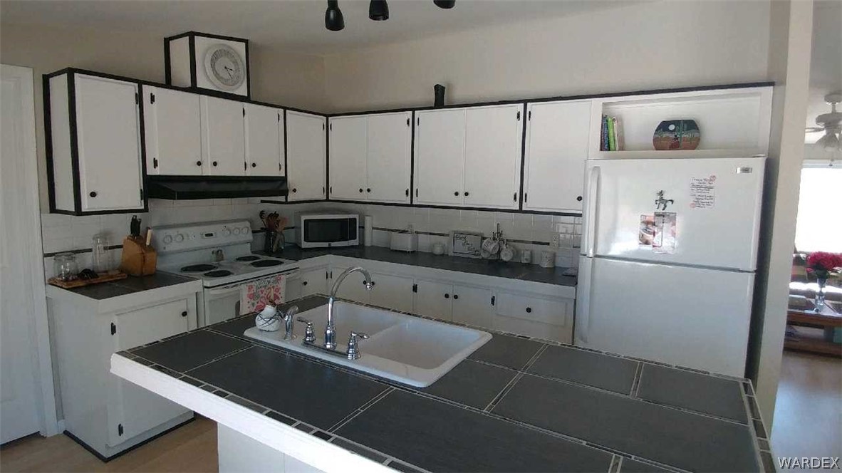3634 Bibo Road Golden Valley, AZ 86413 - Photo 44 of 44 a kitchen with granite countertop a refrigerator a stove a sink and white cabinets