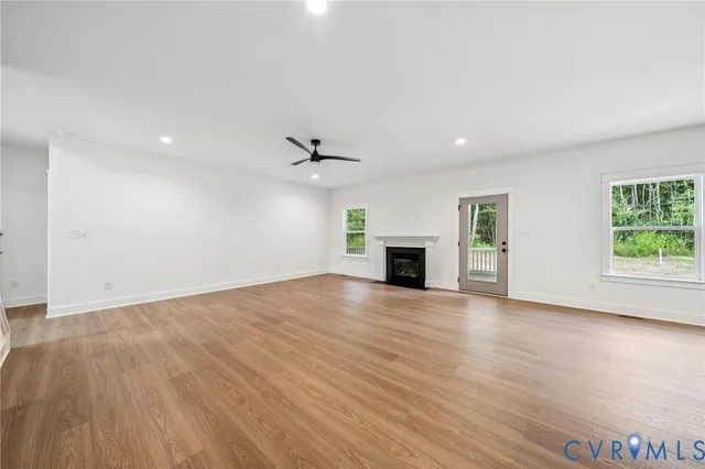 an empty room with wooden floor fireplace and windows