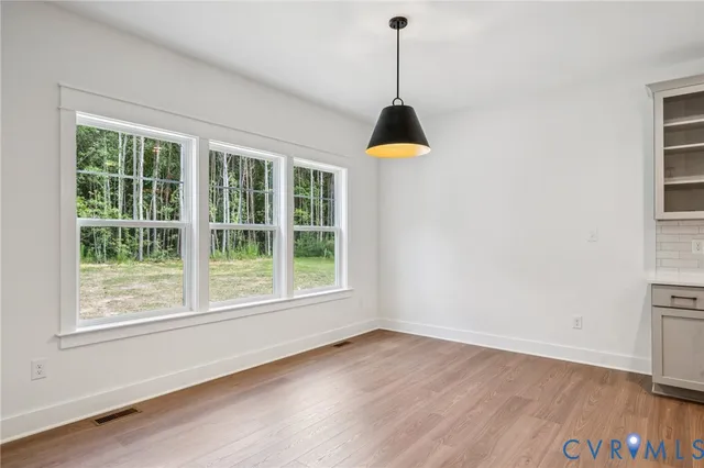 a view of empty room with wooden floor and windows