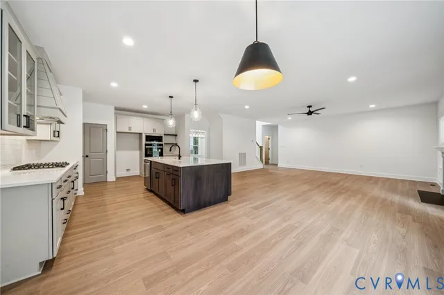 a large kitchen with kitchen island a stove a sink a refrigerator and a wooden floor