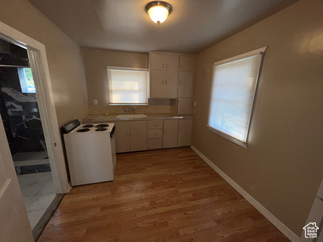 642 East 700 North Logan, UT 84321 - Photo 21 of 33 Kitchen featuring light countertops, white range with electric cooktop, light wood-style floors, and white cabinetry