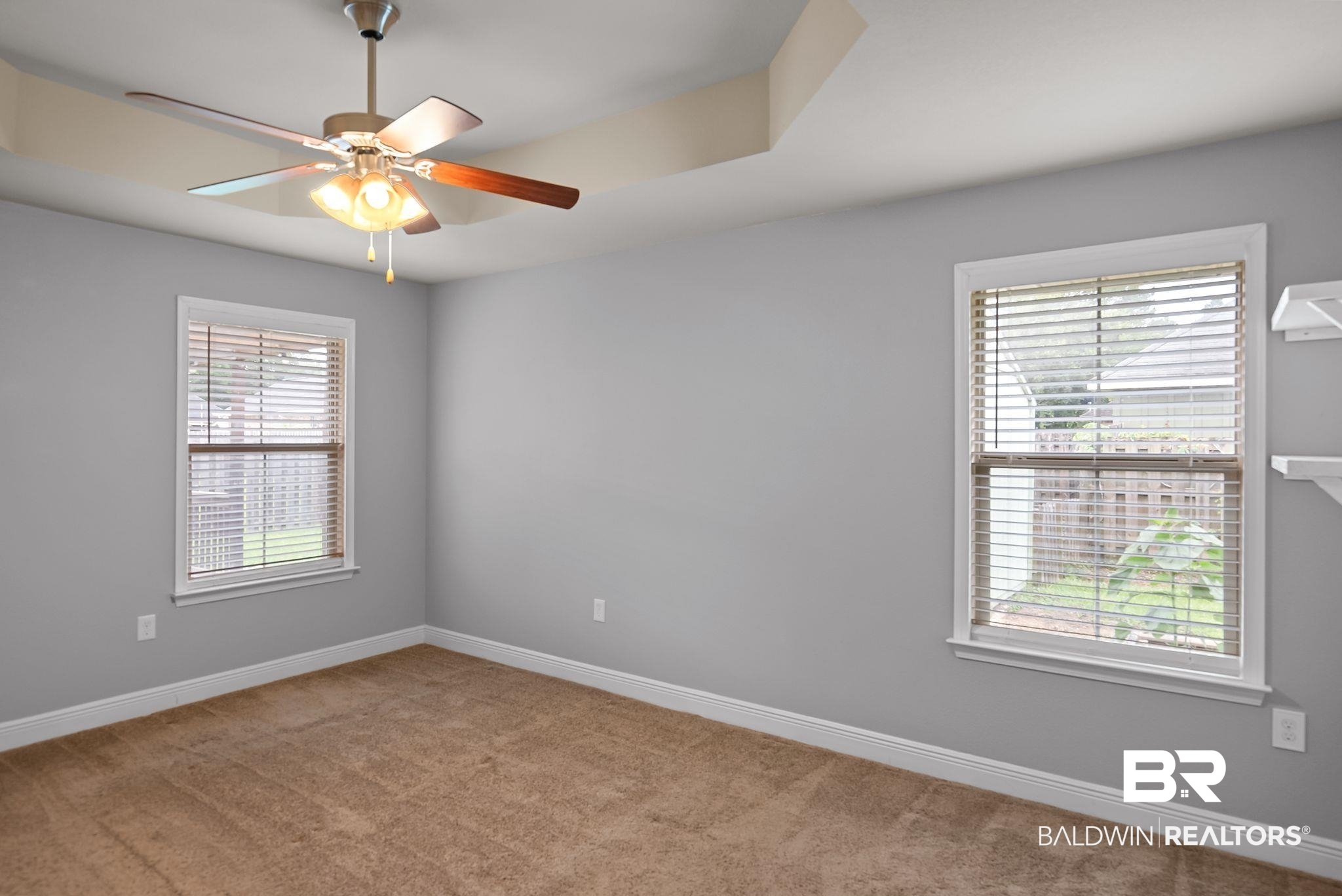 22076 Garland Loop Silverhill, AL 36576 - Photo 12 of 27 Bedroom featuring a tray ceiling, ceiling fan with light fixture, two windows with blinds, built-in shelving, and carpet flooring