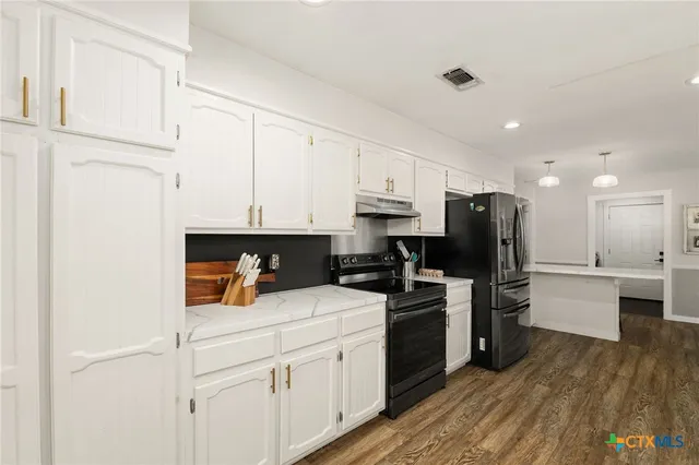 a large kitchen with sink cabinets and wooden floor