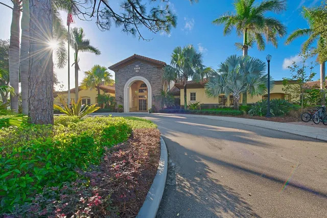 a front view of a house with a garden and palm trees