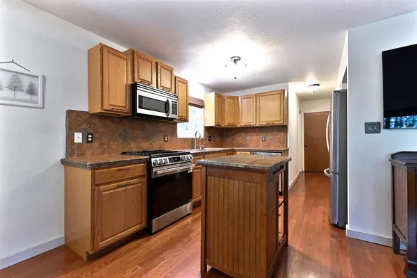a kitchen with stainless steel appliances granite countertop a stove a sink and a refrigerator