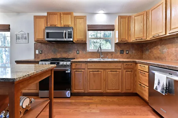 a kitchen with stainless steel appliances granite countertop a stove a sink and a microwave