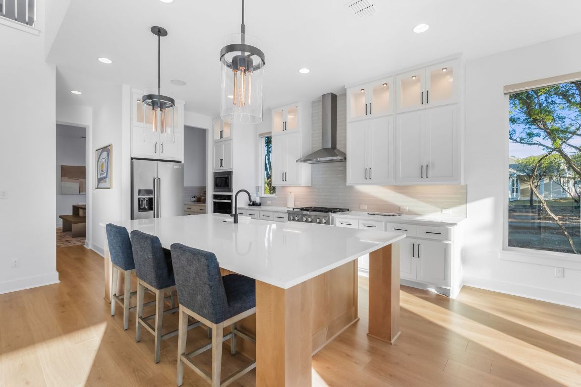 4612 Destination Way Jonestown, TX 78645 - Photo 12 of 37 a kitchen with kitchen island granite countertop a table chairs sink and cabinets