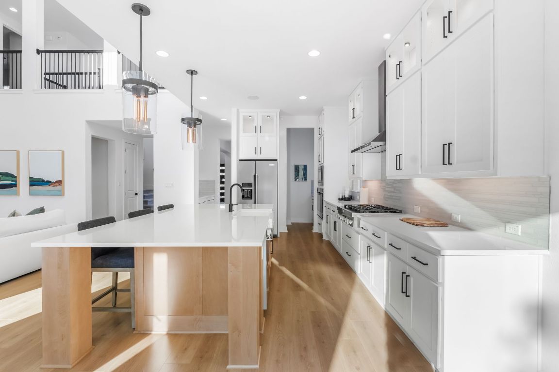 4612 Destination Way Jonestown, TX 78645 - Photo 8 of 37 a large kitchen with stainless steel appliances kitchen island granite countertop a lot of counter space and wooden floor