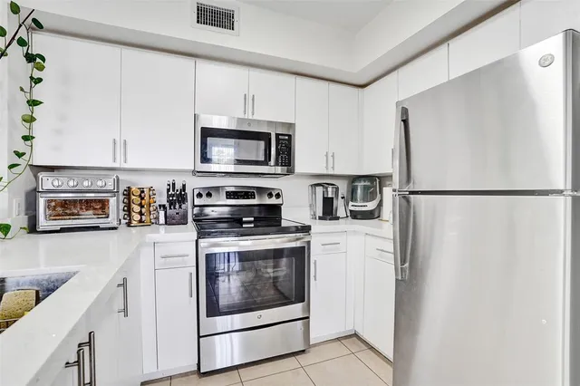 a kitchen with cabinets stainless steel appliances and a counter space